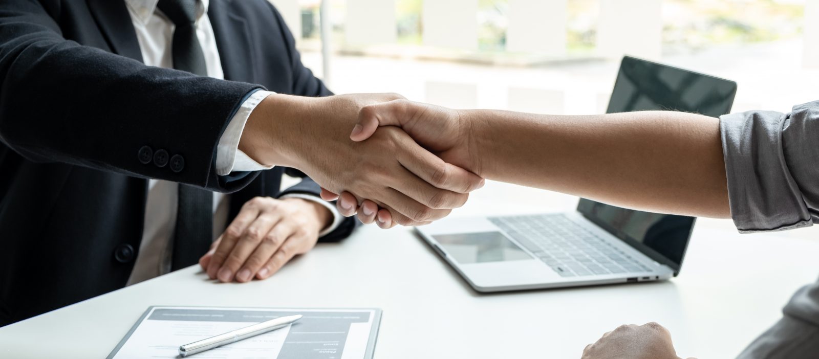 A recruiter meets with a candidate displayed by a close up of a handshake