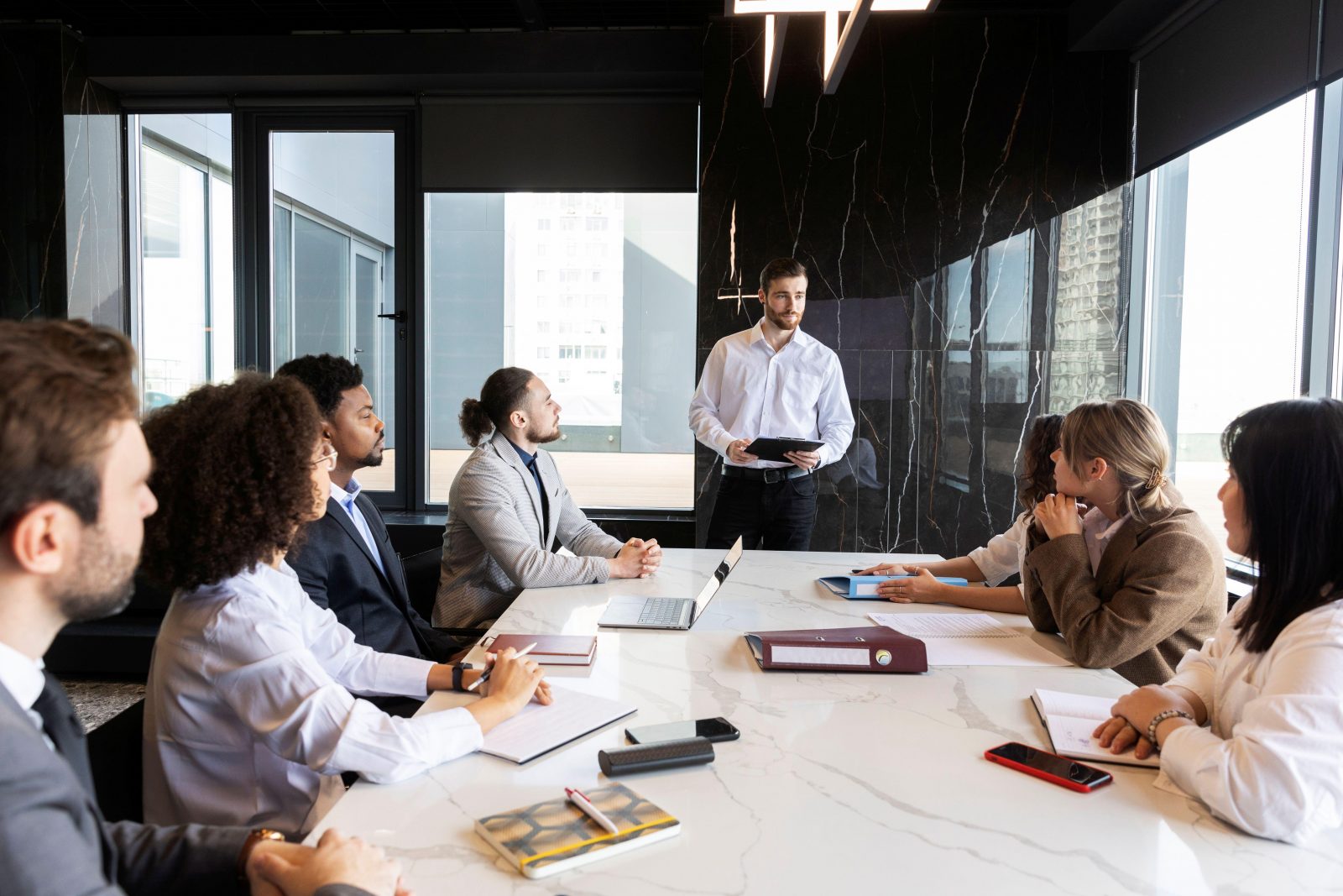 A group of c-suite members of varying ages gathered around a board room table