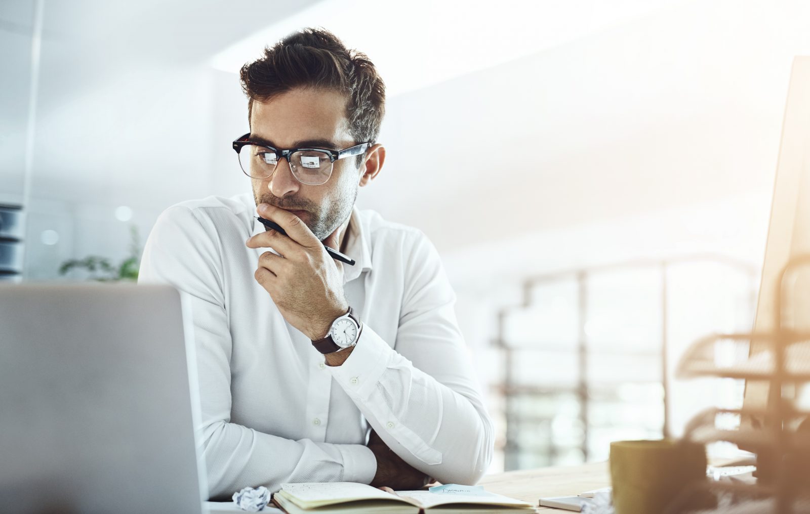 A man in a white shirt sits at his laptop researching his prospective new employer